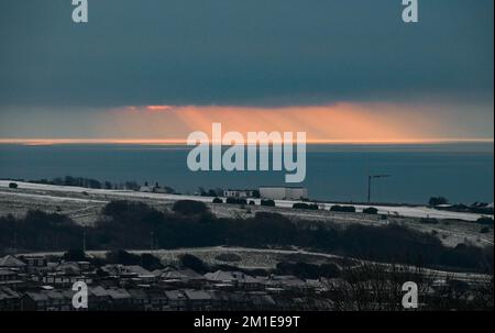Brighton UK 12th December 2022 - The sun rises out at sea after a snowfall in Brighton as the freezing weather is forecast to last for the next few days throughout Britain . : Credit Simon Dack / Alamy Live News Stock Photo