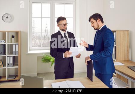 Business colleagues discuss and review paper documents while working in office or law agency. Stock Photo