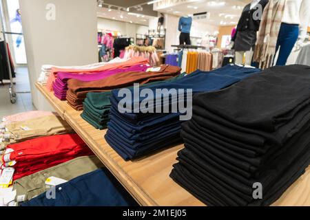Trousers of different colors are on a shelf in a clothing store in a shopping center Stock Photo
