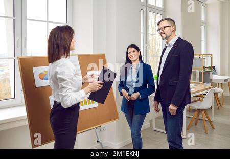 Businesswoman standing near whiteboard discussing new project with her colleagues Stock Photo