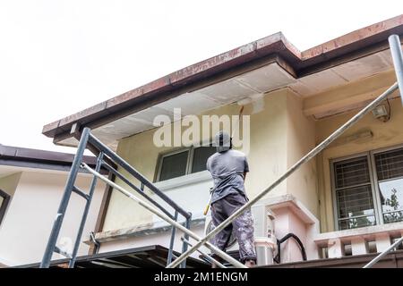 Painter worker adding undercoat foundation paint onto ceiling with roller at residential building Stock Photo