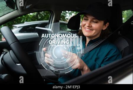 Woman driver controls an autonomous car using a smartphone Stock Photo