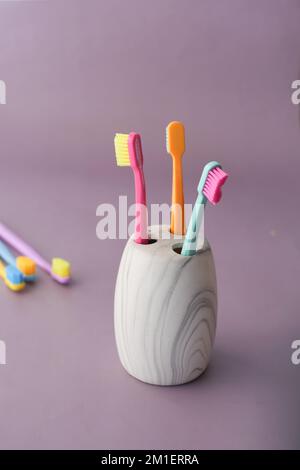 colorful toothbrushes in white mug against a wall Stock Photo - Alamy