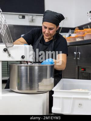 Woman Baker In Mixing Machine Stock Photo