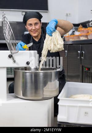 Woman Baker In Mixing Machine Stock Photo