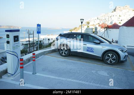 An electric car (a Wolkswagen carbon neutral electric car) charges up using a street juice point in Astypalea, Dodecaneso, Greece Stock Photo