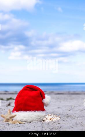 Santa Claus hat and starfish on the sandy beach Stock Photo