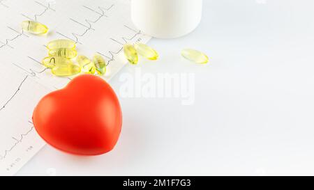 Vitamins and supplements for heart health. White bottle with healthy supplements in gel capsules, cardiogram and decorative heart on doctor desk with Stock Photo