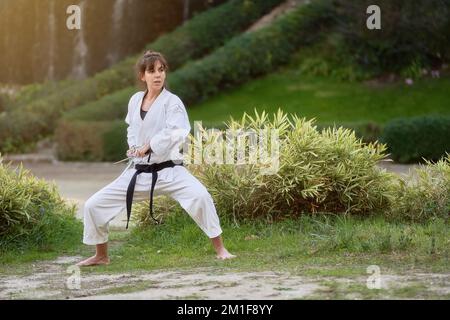 Young karate woman in fighting stance holding a pair of sai outdoors. High quality photo Stock Photo