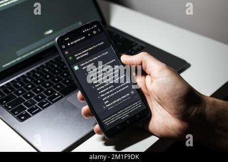 Screen with ChatGPT chat with AI or artificial intelligence. Man search for information using artificial intelligence chatbot developed by OpenAI Stock Photo