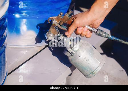 Hand painter with gun sprayer close-up. Professional coloring. Background. Stock Photo