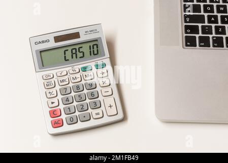 Casio Calculator on desktop, next to laptop computer. Casio is a Japanese multinational electronics manufacturing corporation, founded in 1946. Stock Photo