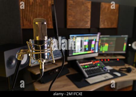 Professional microphone in a small music sound production studio workstation - digital equipment in the production studio room, with mixer, computers Stock Photo