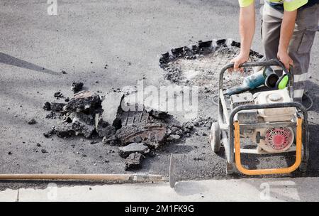 worker in uniform and electric generator machine with asphalt at construction site Stock Photo