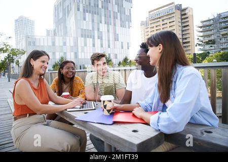 Group of cheerful students studying together outdoors. College classmates review for exam together Stock Photo