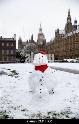 London, UK, 12 December 2022, Snowmen on College Green in a red scarf and beret with Houses of Parliament and Big Ben in the distance. Stock Photo