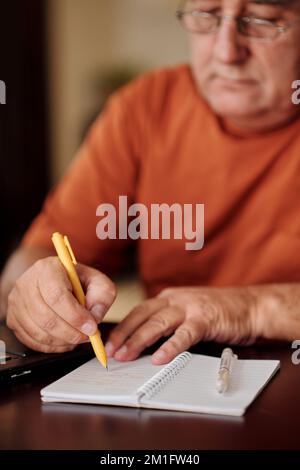 Senior man writing e-mail password in notepad to remember Stock Photo