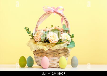 Easter composition. Basket of roses and eggs on the table. Stock Photo
