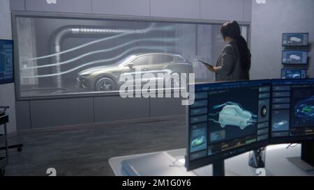 Car design engineers in a lab testing the aerodynamics and body of a ...