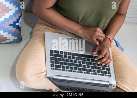 Unrecognizable woman working at home with a laptop on a floor. Writing an email. Stock Photo