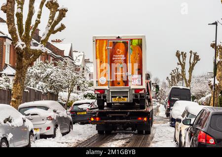 A large truck rescues a sainsbury van in thick snow.The small van is carried piggy back on the big truck's flat surface Stock Photo