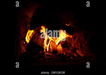 burning firewood in the oven closeup, cozy warmth by the fireplace. Stock Photo