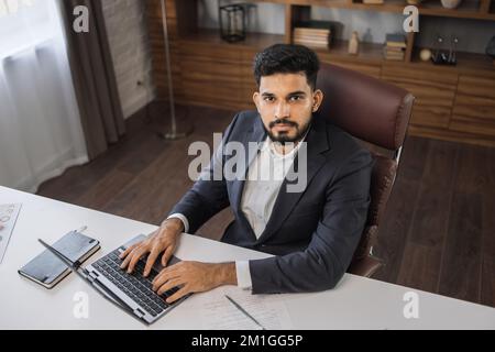 High angle view of stylish bearded businessman works on laptop, data analysis and creative designer, looking at computer. Digital entrepreneur working on e-commerce startup project Stock Photo