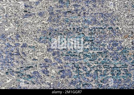 Texture of abstract, decorative velours multi-colored carpet fabric background. Close up of beautiful old blue and beige pile rug with barely visible pattern. Concept of background and textures. Stock Photo