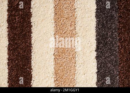 Motley striped carpet background, with thik pile texture. Close up of shaggy beige, white and brown rug, wool fabric texture, fragment for backdrop. Concept of textures and backgrounds. Stock Photo