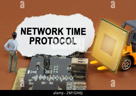 Computer concept. On the board with microcircuits lies a paper plate with the inscription - Network Time Protocol. Nearby is a toy loader with a proce Stock Photo