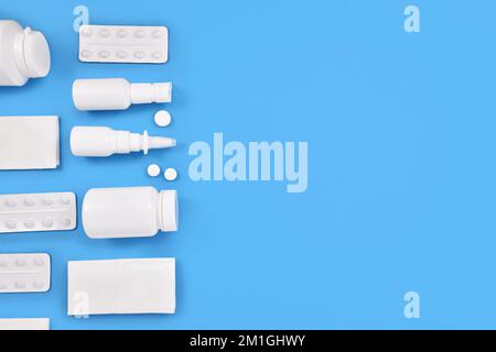 Medication for cold and flue. Nasal spray, throat spray, pills and tissues on blue background with copy space Stock Photo