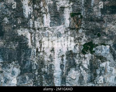 Surface of weathered old stone ancient building wall covered with mold and smudges. Stock Photo