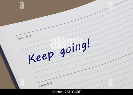 Keep going diary reminder message open on desk Stock Photo