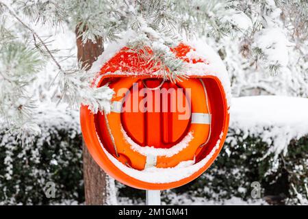 Lifebouy in thick snow near the pond in Alexander Palace.Ready and brightly red coloured with accessibility if there is an emergency or an accident Stock Photo