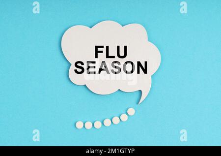 Medicine and health concept. On a blue table are pills and a white plate with the inscription - FLU SEASON Stock Photo