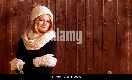 girl in winter clothes knitted hat and warm gloves on wooden background. Stock Photo