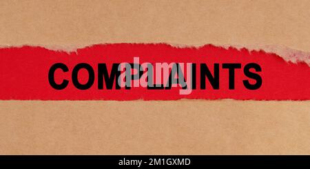 Law concept. Among the torn sheets of paper on a red background, the inscription - COMPLAINTS Stock Photo