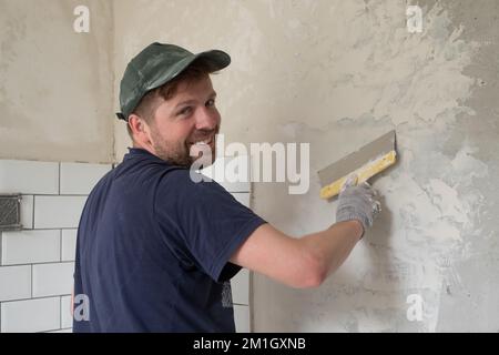 Caucasian man put plaster patching up the cracks on the wall. Stock Photo