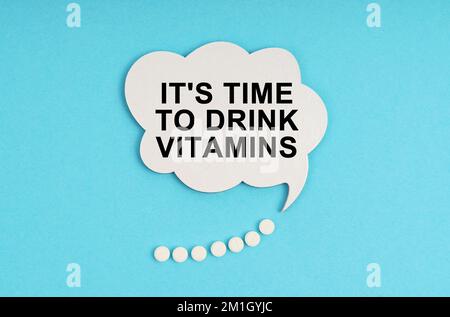 Medicine and health concept. On a blue table are pills and a white plate with the inscription - It s time to drink vitamins Stock Photo