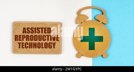 Medicine and health concept. On the white and blue surface are an alarm clock and a sign with the inscription - Assisted Reproductive Technology Stock Photo