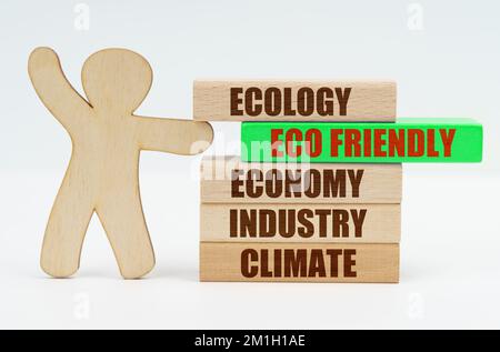 Ecology and industry concept. The wooden man moves the green block with the inscription - ECO FRIENDLY Stock Photo