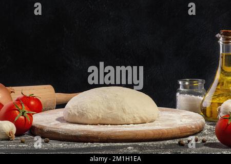 Dough and ingredients for making pizza on a black background. Stock Photo