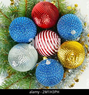 Christmas or New Year ornament. Sprig of spruce and multicolored shiny balls on a white wooden background. Flat lay,top view. Stock Photo