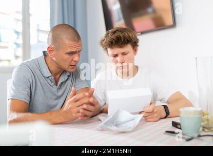 Father reassures his son after reading letter from college Stock Photo