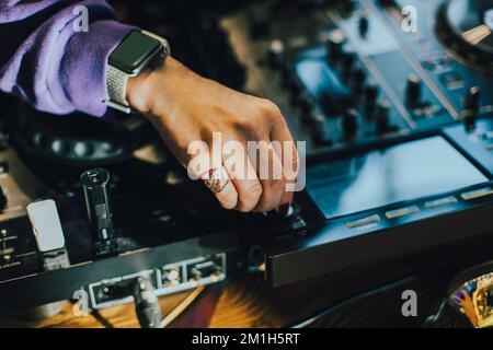 DJ plays live set and mixing music on turntable console on stage at nightclub. Disc Jockey Hands on a sound mixer station at club party. DJ mixer cont Stock Photo