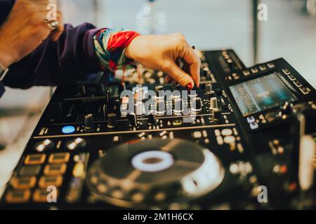 DJ plays live set and mixing music on turntable console on stage at nightclub. Disc Jockey Hands on a sound mixer station at club party. DJ mixer cont Stock Photo