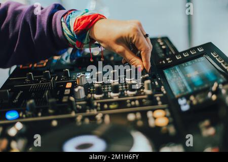 DJ plays live set and mixing music on turntable console on stage at nightclub. Disc Jockey Hands on a sound mixer station at club party. DJ mixer cont Stock Photo