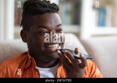 Closeup of happy black man recording voice mail on smartphone Stock Photo