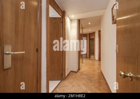 Entrance hall of a house with a long corridor leading to different rooms with oak doors and matching parquet floors Stock Photo