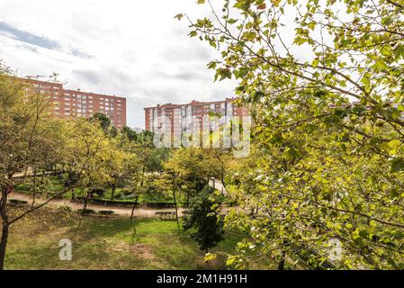 Views of a park with grass, hedges, trees and sandy walks near some apartment buildings Stock Photo